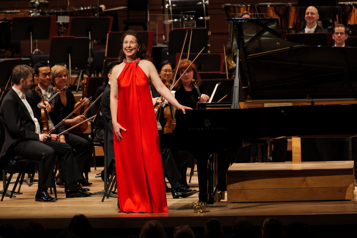 Angela Hewitt en robe rouge devant une piano